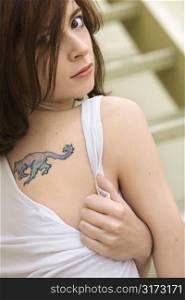Portrait of attractive young redhead Caucasian woman with tattoo on shoulder.