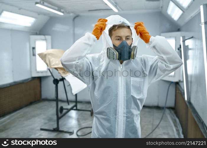 Portrait of automobile painter standing in paint chamber workshop wearing protective uniform.. Portrait automobile painter standing in paint chamber