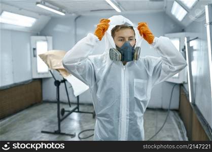 Portrait of automobile painter standing in paint chamber workshop wearing protective uniform.. Portrait automobile painter standing in paint chamber