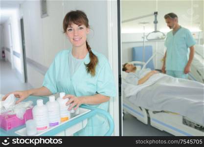 portrait of auxiliary nurse with trolley outside of patients room