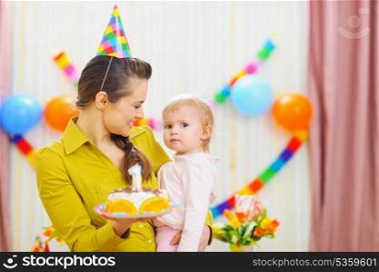 Portrait of baby and mother with birthday party cake