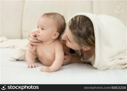 Portrait of baby boy lying on bed with mother
