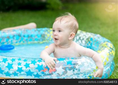 Portrait of baby boy playing in swimming pool at garden