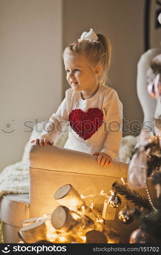 Portrait of baby in Christmas decorations.. The child plays with the ornaments on the Christmas tree 7277.