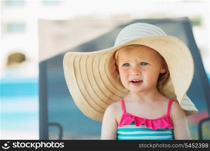Portrait of baby in hat sitting on sunbed