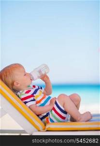 Portrait of baby on sun bed drinking water