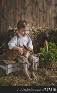 Portrait of baby rabbit among white and hay boxes.. Portrait of a little boy playing with a rabbit 6047.