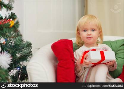 Portrait of baby sitting on chair with Christmas present box