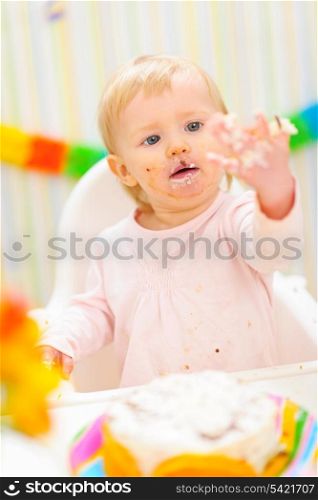 Portrait of baby smeared in birthday cake