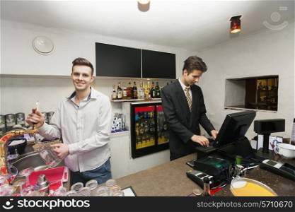 Portrait of bartender with cashier at counter in restaurant