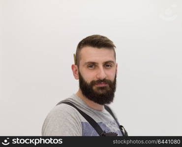 portrait of bearded hipster handyman with pen behind ear isolated on white background