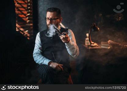 Portrait of bearded man in glasses sitting on a chair and smoking pipe. Writer, journalist, literature author, blogger or poet concept. Portrait of man sitting on chair and smoking pipe