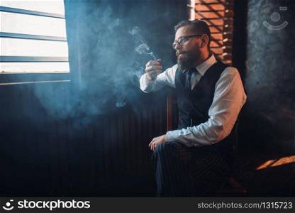 Portrait of bearded man in glasses sitting on a chair and smoking pipe. Writer, journalist, literature author, blogger or poet concept. Portrait of man sitting on chair and smoking pipe