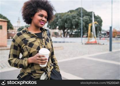 Portrait of beautiful afro american latin woman holding a cup of coffee outdoors in the street. Urban concept.