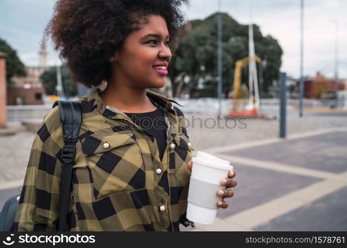 Portrait of beautiful afro american latin woman holding a cup of coffee outdoors in the street. Urban concept.