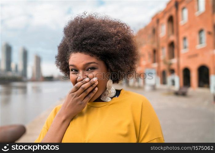Portrait of beautiful afro latin confident woman laughing in the street. Outdoors. Urban concept.
