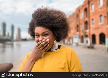 Portrait of beautiful afro latin confident woman laughing in the street. Outdoors. Urban concept.
