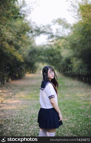 Portrait of beautiful Asian japanese high school girl uniform looking with bamboo forest background
