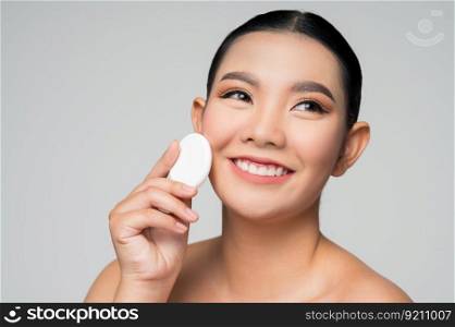 Portrait of Beautiful Asian woman holding foundation or cushion sponge puff. Skin care healthy hair and skin close up face beauty isolated over background. Cosmetology and Spa concept.