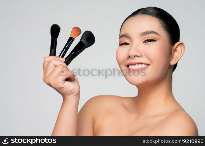 Portrait of Beautiful Asian woman holding makeup blusher brush. Skin care healthy hair and skin close up face beauty isolated over background. Cosmetology and Spa concept.