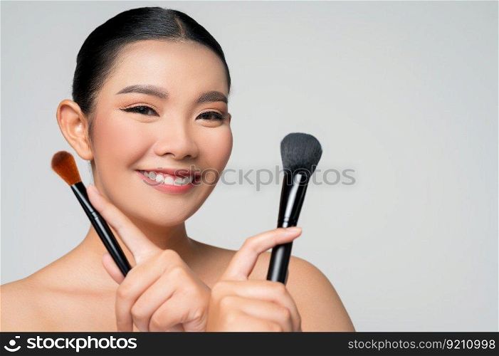 Portrait of Beautiful Asian woman holding makeup blusher brush. Skin care hea<hy hair and skin close up face beauty isolated over background. Cosmetology and Spa concept.