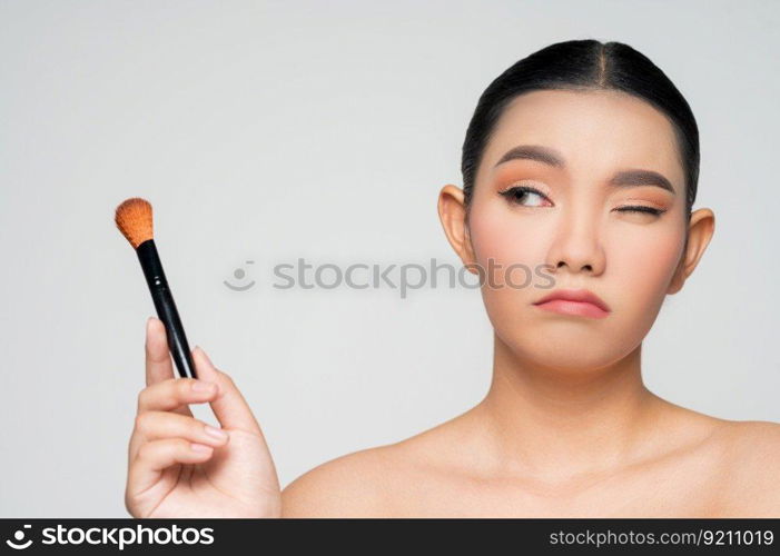 Portrait of Beautiful Asian woman holding makeup blusher brush. Skin care healthy hair and skin close up face beauty isolated over background. Cosmetology and Spa concept.