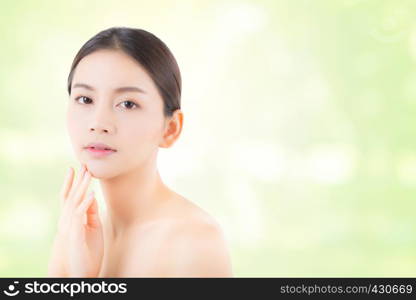 Portrait of beautiful asian woman makeup of cosmetic - girl hand touch mouth or lip and relax on attractive face with skin healthcare concept on green nature background.