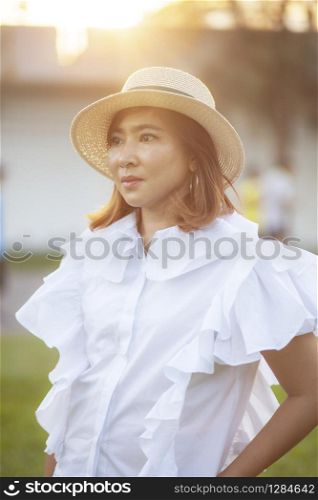 portrait of beautiful asian woman wearing straw hat against beautiful sun light