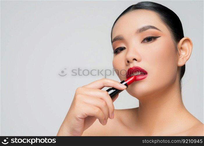 Portrait of Beautiful Asian woman with lipstick in hand. Skin care healthy hair and skin close up face beauty isolated over background. Cosmetology and Spa concept.