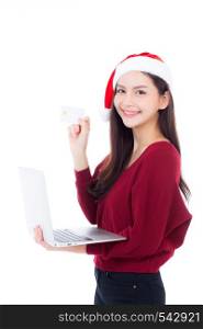 Portrait of beautiful asian young woman in santa hat using laptop computer and holding credit card isolated on a white background, shopping holiday concept.