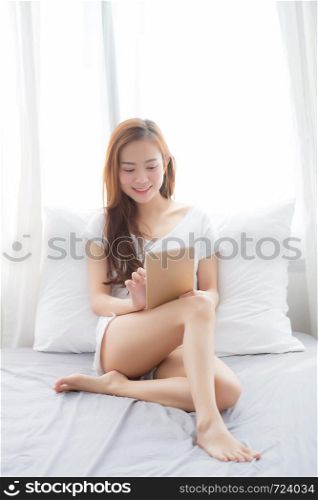 Portrait of beautiful asian young woman with holding and reading digital tablet computer with leisure, girl using tablet with relax at bedroom, lifestyle and communication concept.