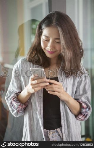 portrait of beautiful asian younger woman reading message in smart phone with smiling and happiness face