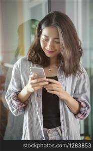 portrait of beautiful asian younger woman reading message in smart phone with smiling and happiness face