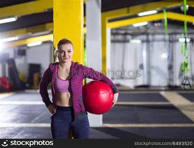 Portrait of beautiful athlete woman with red medicine ball at crossfitness gym. portrait of woman with red crossfitness ball