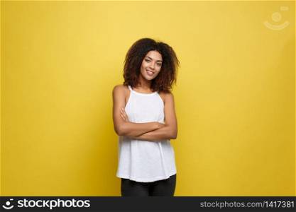 Portrait of beautiful attractive African American woman posting crossed arms with happy smiling. Yellow studio background. Copy Space. Portrait of beautiful attractive African American woman posting crossed arms with happy smiling. Yellow studio background. Copy Space.