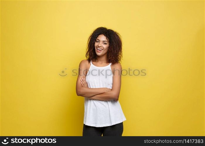 Portrait of beautiful attractive African American woman posting crossed arms with happy smiling. Yellow studio background. Copy Space. Portrait of beautiful attractive African American woman posting crossed arms with happy smiling. Yellow studio background. Copy Space.