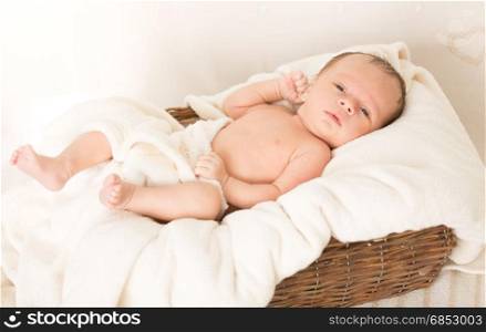 Portrait of beautiful baby boy lying in wicker basket