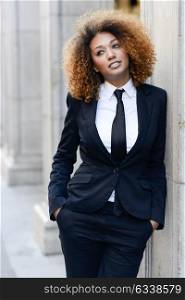 Portrait of beautiful black businesswoman wearing suit and tie in urban background