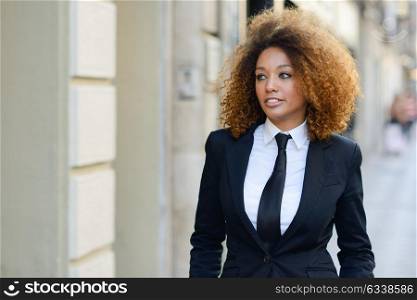 Portrait of beautiful black businesswoman wearing suit and tie in urban background