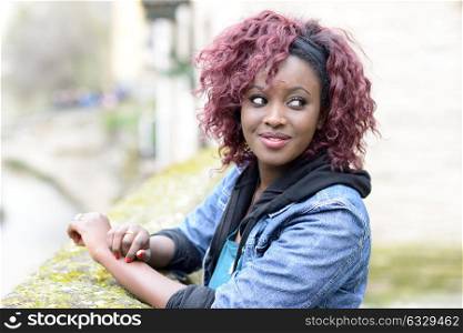 Portrait of beautiful black woman in urban background with red hair