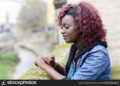 Portrait of beautiful black woman in urban background with red hair