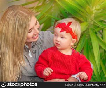 Portrait of beautiful blond female with her little daughter having fun in the park, enjoying motherhood, love and happiness concept