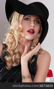 portrait of beautiful blond girl with curly hair and hat with black dress