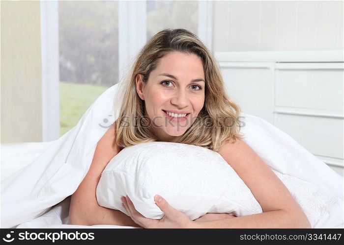 Portrait of beautiful blond woman laying in bed