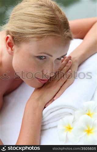 Portrait of beautiful blond woman relaxing on massage bed