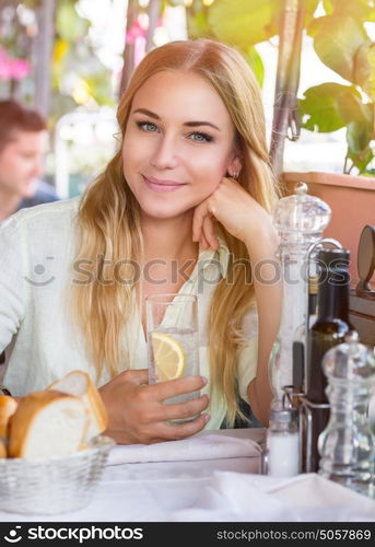 Portrait of beautiful blond woman sitting at outdoors cafe and drink water with lemon, healthy nutrition, traveling to Italy, Europe