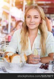 Portrait of beautiful blond woman sitting at outdoors cafe and drink water with lemon, healthy nutrition, traveling to Italy, Europe