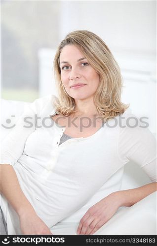 Portrait of beautiful blond woman sitting on sofa