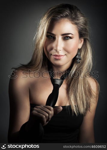 Portrait of beautiful blond woman wearing tie over dark gray background, stylish fashion look, luxury beauty salon