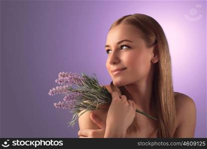 Portrait of beautiful blond woman with lavender flowers isolated over purple background, enjoying day spa